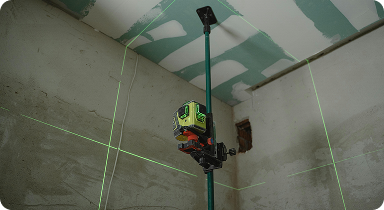 construction worker using laser level tool for wall alignment and drywall installation