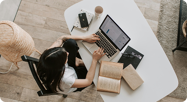 student studying online with laptop and books at home workspace