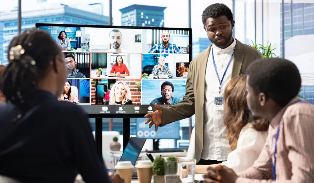 Diverse professional team in a modern office collaborating as a Data Engineer team, using a large screen for a video conference with remote colleagues.